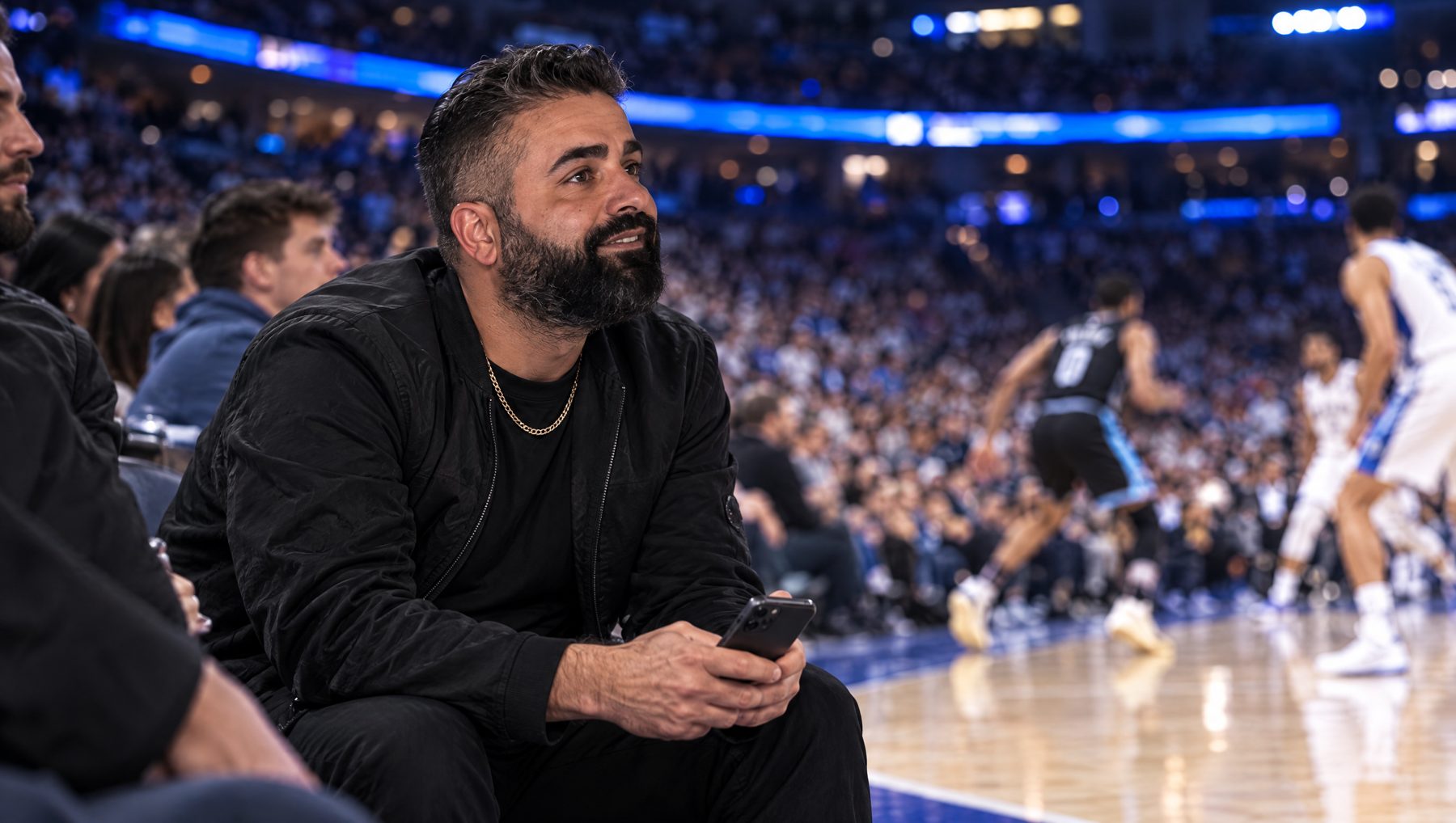 Nicky Brows courtside at a basketball game with phone in hand